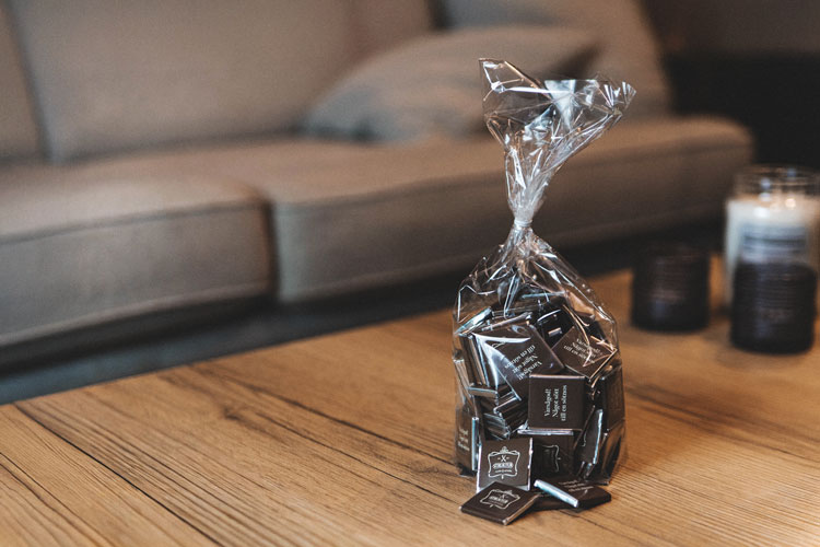 En påse med chokladbitar. Omslagspapperet har Salong Strukturs logga.