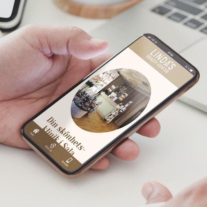 En hand håller en mobil som visar Lindas Beautycenters hemsida.