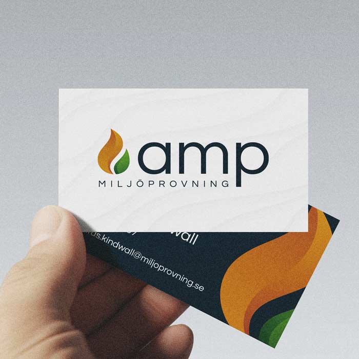 En hand håller i två visitkort med AMPs logga och kontaktuppgifter